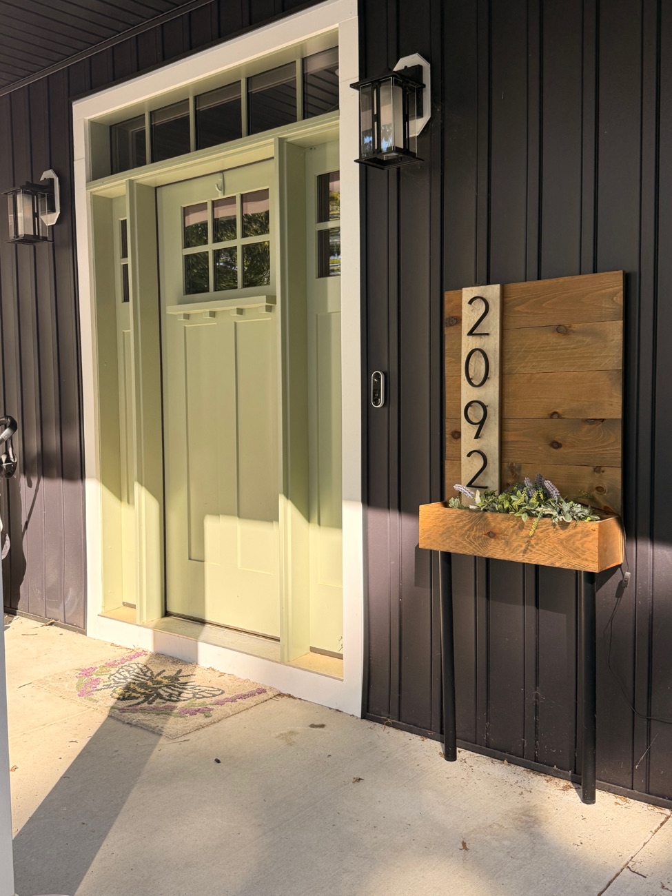A custom Rent Delaware Beaches house number sign reading 2092, built from stained wood with a vertical number panel and a matching planter box, mounted beside a front door.